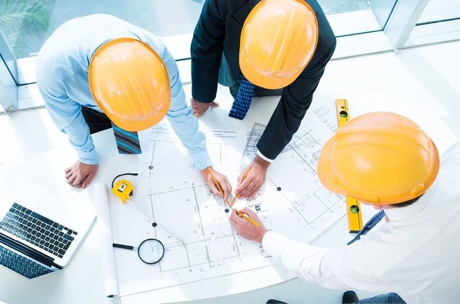 Kỹ sư công trường đội mũ bảo hộ trao đổi bản vẽ — hợp tác nhà thầu thiết bị bếp Le Phan Living